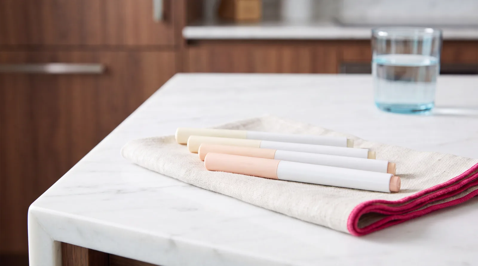 Four plain weekly injector pens lined up on a marble counter, one for each dose step