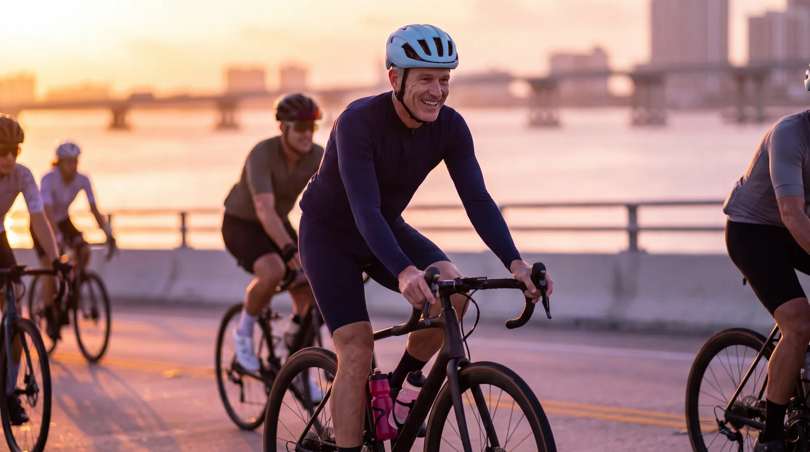 Man in his fifties cycling the Rickenbacker Causeway with a group at sunrise