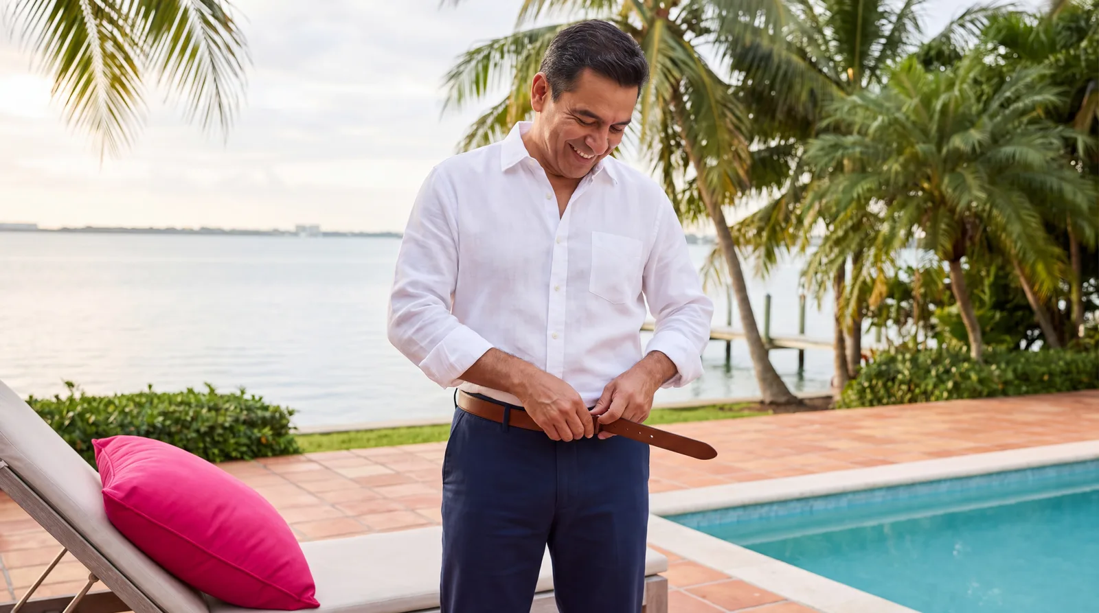 Man in his fifties tightening his belt a notch on his terrace, pleased with his weight loss