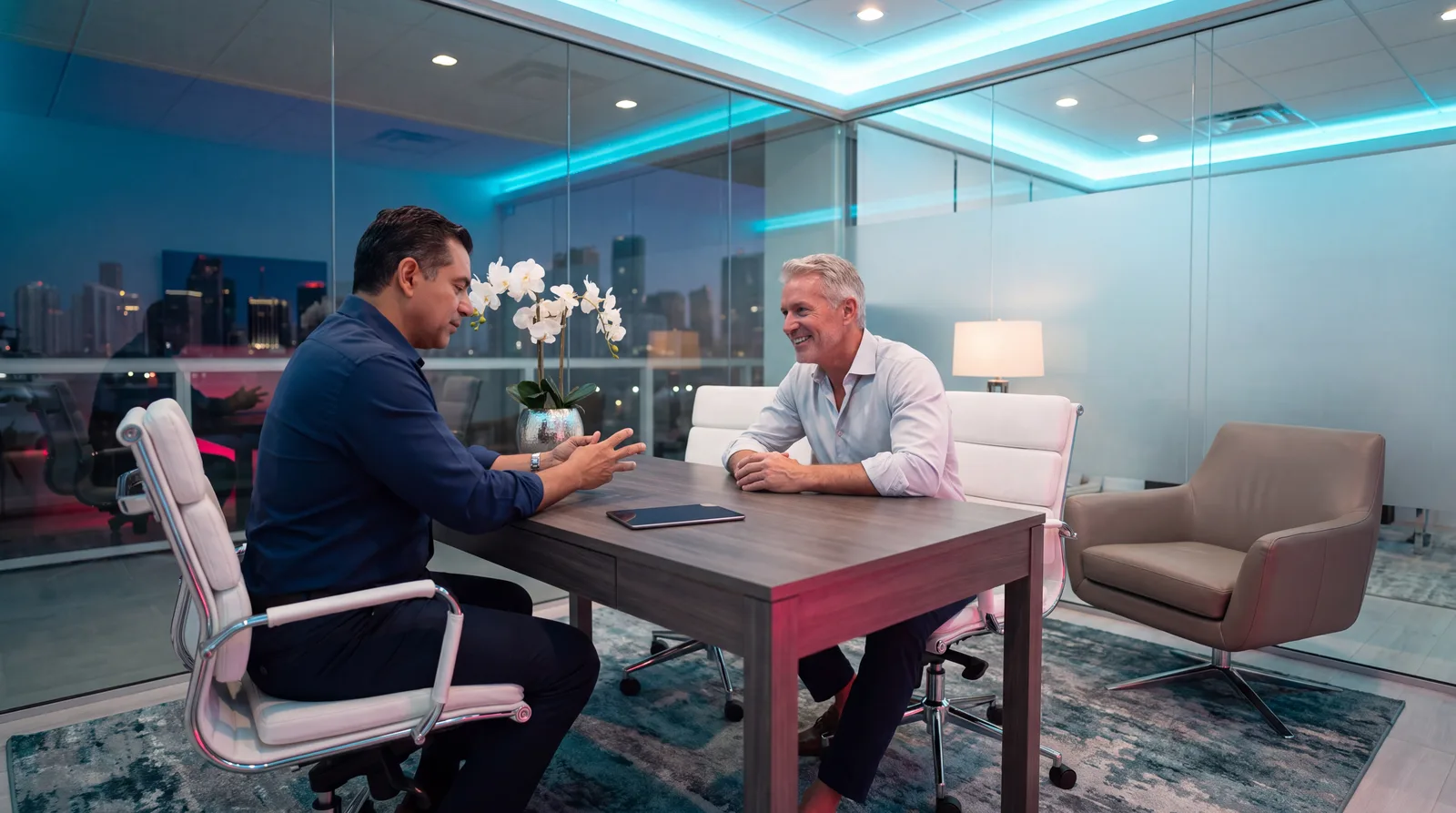 Doctor and patient talking across a dark wood table in a glass-walled Miami consultation room